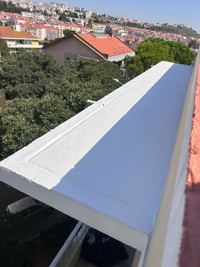 Platibanda de cobertura com membrana de impermeabilização aplicada a meio, a mostrar a zona já tratada e a zona por tratar