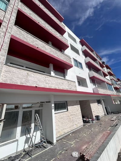A mesma fachada depois da obra, com reboco reparado, pintura branca nova e as palas das varandas pintadas de vermelho