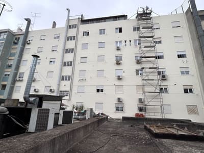 Prédio de habitação com a fachada acabada de pintar e um andaime móvel montado junto à empena