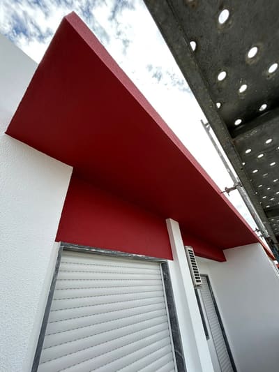 Pala de varanda pintada de vermelho vista de baixo, com o andaime montado ao lado da fachada